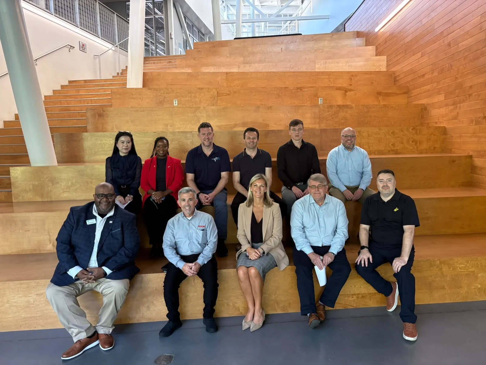 The delegation seated on the wooden stepped seating in the atrium at CU-ICAR.
